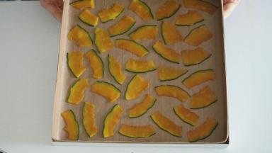 然后再将南瓜片无规则的摆放在烤盘上，注意尽量把南瓜片贴紧油布，这样出来的蛋糕卷表面会更加平整，然后我们连同烤箱放入冰箱冷藏备用