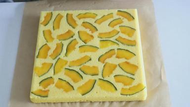 立即轻轻的撕开油纸，因为南瓜片本身含有水分，如果不撕开晾凉，会造成蛋糕卷表面过于湿润，撕开的时候要慢一点，以免南瓜片站在油布上一同被带走