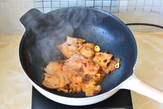 加入切好的肉片和蒜片下锅，翻炒至肉片卷曲，肥肉透明最好，这样猪肉的油都被炒出来了，吃起来不腻。