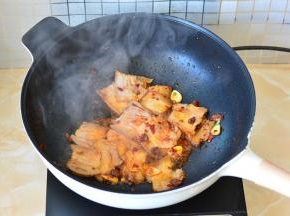 加入切好的肉片和蒜片下锅，翻炒至肉片卷曲，肥肉透明最好，这样猪肉的油都被炒出来了，吃起来不腻。
