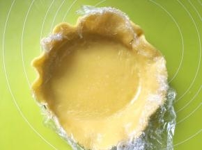 揭掉一层保鲜膜，将面皮盖在蛋挞模具上