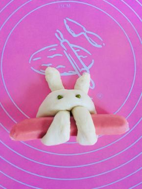 取两颗绿豆按压在半圆上，当做小兔子的眼睛