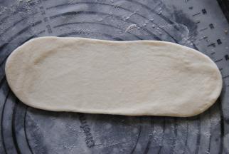 取一个面团，用擀面杖擀成20CM长度的长舌状。