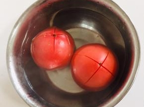 西红柿顶部用刀划十字刀，放在容器中，倒入开水烫一分钟左右。