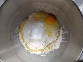 将牛奶、酵母粉、高筋粉、盐糖和鸡蛋、玉米油，依次倒入厨师机搅拌桶内。盐糖不要接触酵母粉，中间最好用高筋粉隔开，以免影响发酵效果。