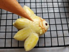 将烤好的小鱼取出，放在晾网上晾凉。同时将橘色巧克力切碎，用微波炉小火融化成液体后，装入剪小口的裱花袋中。