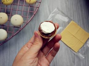 将奶酪片切成适当大小，将巧克力酱在一片上挤出空心圆，内芯填充打发的淡奶油或果酱，或其他奶油霜馅料（依个人喜好）。再用调色的淡奶油模仿菜叶，装饰在边缘，盖上上盖即可。