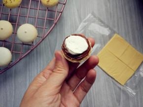 将奶酪片切成适当大小，将巧克力酱在一片上挤出空心圆，内芯填充打发的淡奶油或果酱，或其他奶油霜馅料（依个人喜好）。再用调色的淡奶油模仿菜叶，装饰在边缘，盖上上盖即可。