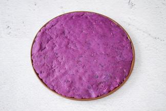 把紫薯泥均匀的铺上披萨盘上，用勺子压实了