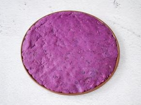 把紫薯泥均匀的铺上披萨盘上，用勺子压实了