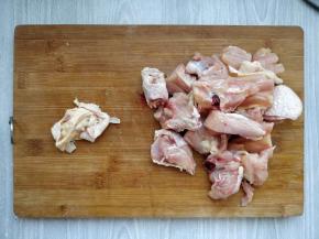 先将鸡大腿用水冲洗一下，用刀刮掉多余的肥油，再用斩骨刀纵向剁成大块，把骨头旁边的肉分成小块。
