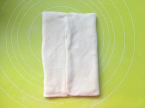 将两侧的面片像中间对折，包裹上黄油，对折处一定要捏紧，之后室温软化10分钟，让黄油软化一些
