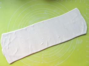撒干粉，将松弛好的面片接口处朝下，擀成长条，长度50厘米左右
