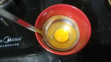 汤勺里抹上油，打入一个鸡蛋