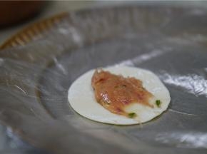 将调好味的番茄肉馅包在饺子皮里。