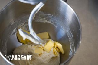 用厨师机低速搅拌成团，再中速搅打2分钟，放入软化的黄油继续搅打。