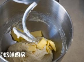 用厨师机低速搅拌成团，再中速搅打2分钟，放入软化的黄油继续搅打。