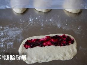 取一个醒发后的面团，压扁擀开成长方形，中间放一点果酱。