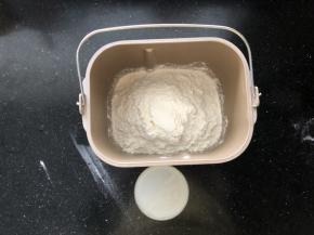 7、接下来制作烩面的面胚。把食用碱和盐倒入温水中融化，面粉放入面包机中。