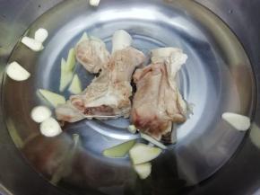 锅里加入适量的水，把姜和蒜片，还有大骨放入锅中