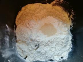 再加入高筋面粉，在面粉中间挖个小洞，加入干酵母，用面粉把干酵母盖起来，启动面包机的“自动和面”程序15分钟。