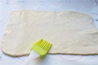 白色面团擀成均匀的薄片，表面刷上一层薄油，撒少许椒盐粉。卷起来成为一个卷。