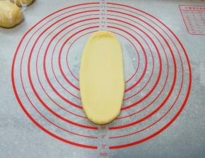 取一份面团压扁，擀成牛舌状。