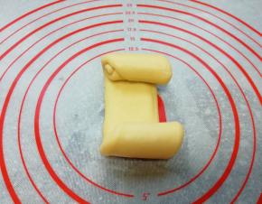 继续压扁擀开成牛舌状，从两头往中间卷起。