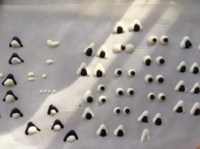 裱花袋转入一点点融化的黑巧克力，在白色眼球上点上一点点，做为眼睛，三角的内部也可以挤上一点，耳朵也可以将黑巧克力挤在外层，白色添充内部