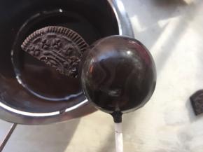 将饼干的平角部分蘸上一点点热巧克力，点在棒棒糖一侧，做小蝙蝠的翅膀，等巧克力干透，再粘上另外一侧的饼干
