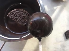 将饼干的平角部分蘸上一点点热巧克力，点在棒棒糖一侧，做小蝙蝠的翅膀，等巧克力干透，再粘上另外一侧的饼干

