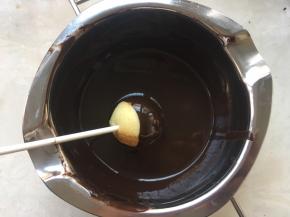 取一个棒棒糖，在巧克力内滚一下，让蛋糕滚满巧克力，纸棒跟蛋糕接口处也要滚上一点，这样可以防止蛋糕脱落，让蛋糕跟纸棒充分粘合在一起
