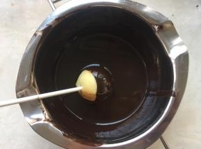 取一个棒棒糖，在巧克力内滚一下，让蛋糕滚满巧克力，纸棒跟蛋糕接口处也要滚上一点，这样可以防止蛋糕脱落，让蛋糕跟纸棒充分粘合在一起
