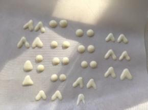 取一张油纸，取一点点白巧克力装入裱花袋放入热水内融化，白巧克力的用量特别少，这样融化更方便，之后将裱花袋剪个小口，很小的小口，在油纸上挤上一些圆点点做眼球，再挤上一些小三角做耳朵，巧克力凉透轻抖油纸就下来啦