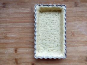 将面片放入模具中，底部、四周和边缘按平，用擀面杖在模具边缘擀一下，去除多余的面片。底部用叉子扎一些小孔，以免烘烤时鼓起。