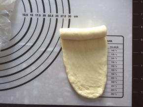 松弛好后，拿出一个面团，擀成牛舌状，从上向下卷起