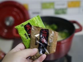 然后加入泡菜及二份料包，拌至面条挂味就可以。