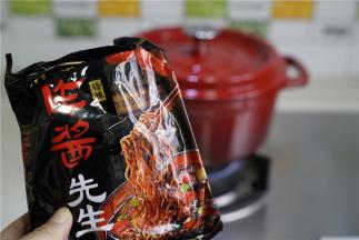 珐琅锅里加水煮开，炸酱面的料包取出，将面下锅，焖煮三分钟。珐琅锅密封性好，不用煮太长时间。