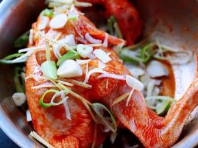 这个时候把用刀切好的葱花，大蒜和姜片撒在鸡的身上。