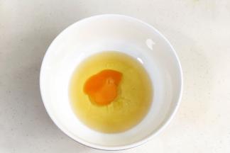 在花生油中加入鸡蛋，用手动打蛋器搅拌均匀。