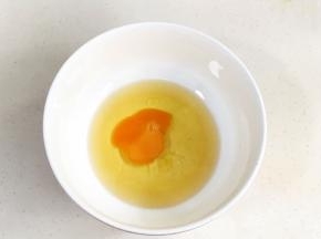 在花生油中加入鸡蛋，用手动打蛋器搅拌均匀。
