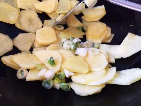 锅中放油烧热，放入葱碎和土豆片翻炒两分钟