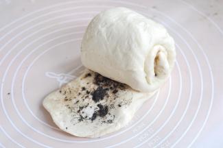 将面的一边按压扁，并扯大，从另一头卷起，用扯开的面皮将整个面团包起来。