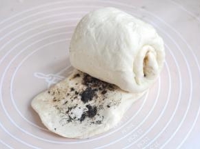 将面的一边按压扁，并扯大，从另一头卷起，用扯开的面皮将整个面团包起来。