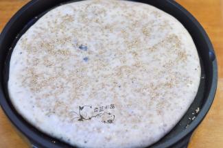 同时，饼面上刷一层水，撒上白芝麻，轻轻按压几下。翻面后继续烘烤2分钟即可。