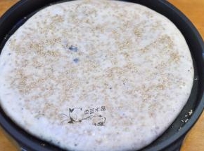 同时，饼面上刷一层水，撒上白芝麻，轻轻按压几下。翻面后继续烘烤2分钟即可。