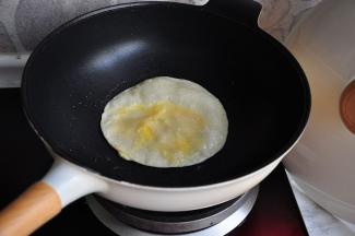 调成小火，用筷子将饼戳破，快速将提前打散的蛋液倒入并使其均匀。