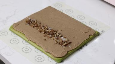 20.	晾凉的栗子泥涂抹在整个蛋糕卷上，注意：卷起一侧的馅料是最厚的，收尾一侧是最薄的。在靠近卷起一侧的1/3位置放上栗子碎，（栗子煮的时候没有加糖，所以栗子碎我额外加了一些白糖拌匀）。然后用擀面杖辅助卷起。卷的手法大家可以网上找视频看看