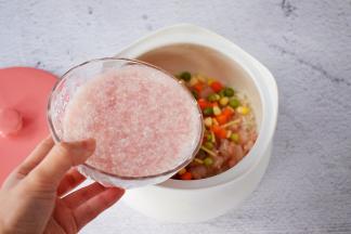 把大米淘洗干净放入炖盅中，加入虾仁、玉米粒、豌豆、胡萝卜、姜丝，再倒入猪肉末水