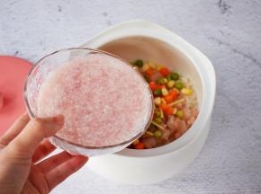 把大米淘洗干净放入炖盅中，加入虾仁、玉米粒、豌豆、胡萝卜、姜丝，再倒入猪肉末水